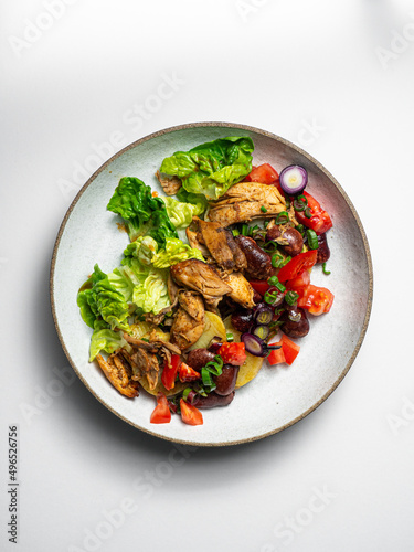 Grilled Chicken Salad - with tomatoes, potatoes, beans, onions  On a ceramic plate, with a white  background photo