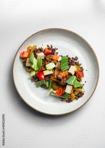 Quiona salad with smoked tofu, tomatoes, pak choi, fennel, mushrooms. On a ceramic plate, with a white  background photo