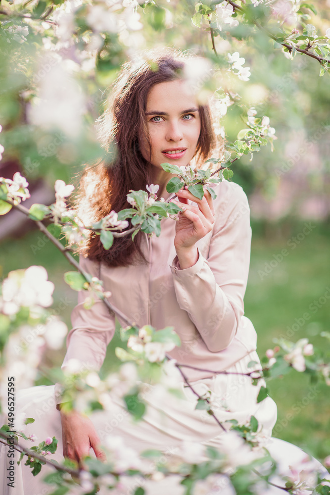 Tenderness itself. A young woman sniffs the aroma in a blooming apple garden in spring Tenderness itself. A young woman sniffs the aroma in a blooming apple garden in spring