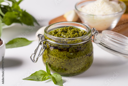 Basil pesto sauce in a jar. Ingredients for cooking, cheese, parmesan, garlic, olive oil. 