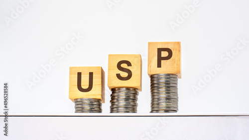 rising stacks of coins with the letters USP on the wooden cubes, white background, business and finance concept