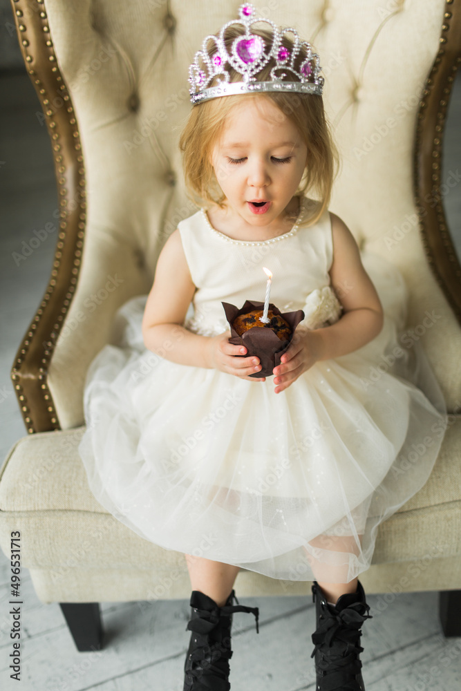 young princess celebrates her birthday. blows out the candle on the cake