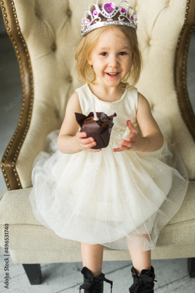 young princess celebrates her birthday. blows out the candle on the cake