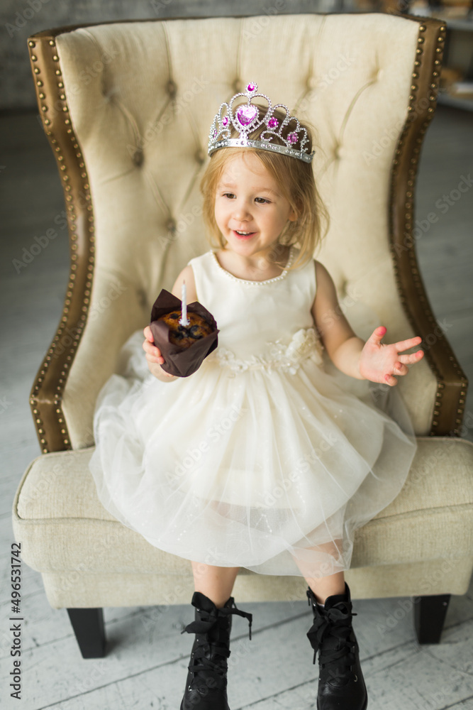 young princess celebrates her birthday. blows out the candle on the cake