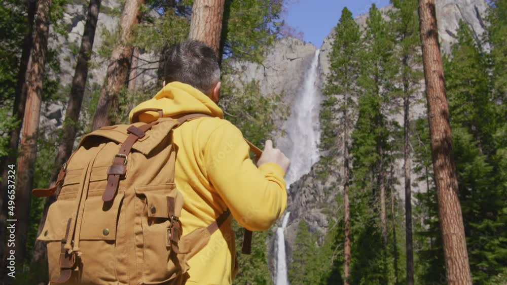 Handsome male traveller with backpack at Yosemite waterfall, in National park Handsome male traveller with backpack at Yosemite waterfall, in National park
