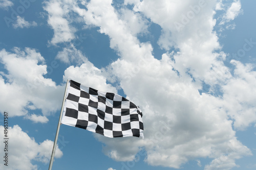 checkered flag on cloudy blue sky background