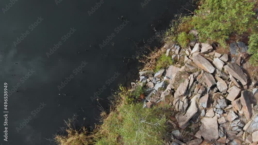 Flooded granite quarry top down view. Scattered pieces of granite after mining. Rocky high stone shores of lake Flooded granite quarry top down view. Scattered pieces of granite after mining. Rocky high stone shores of lake