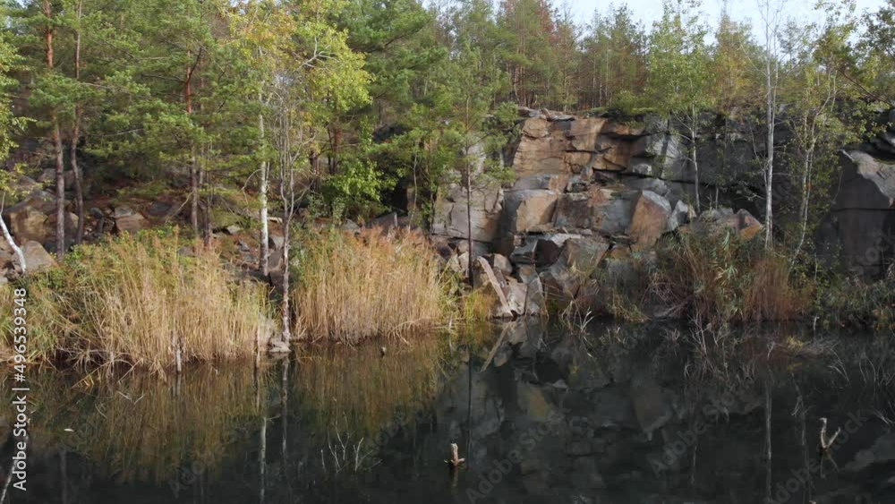 Low pass at lake surface of old granite quarry in Ukraine. Scattered pieces of granite after mining old USSR quarry Low pass at lake surface of old granite quarry in Ukraine. Scattered pieces of granite after mining old USSR quarry