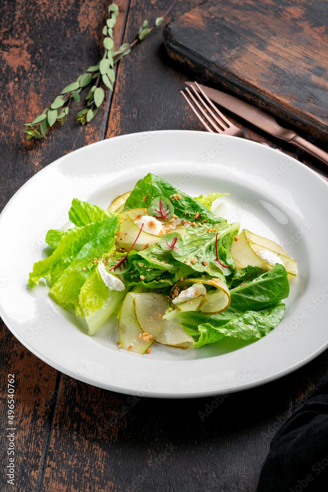 Fresh green salad with pear, rocket leaves, cheese and nuts on a white plate Fresh green salad with pear, rocket leaves, cheese and nuts on a white plate