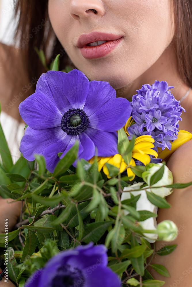 Portrait of beautiful lady covering bare breast with bouquet of bright wildflowers. Attractive woman with perfect makeup and natural accessory. Fashion photo, posing on white background in studio Portrait of beautiful lady covering bare breast with bouquet of bright wildflowers. Attractive woman with perfect makeup and natural accessory. Fashion photo, posing on white background in studio