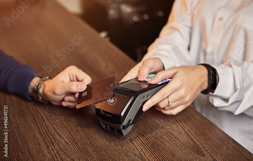 The customer's hand pays for a contactless credit card with NFC technology. Bartender with a Credit Card reader. Focus on hands.
