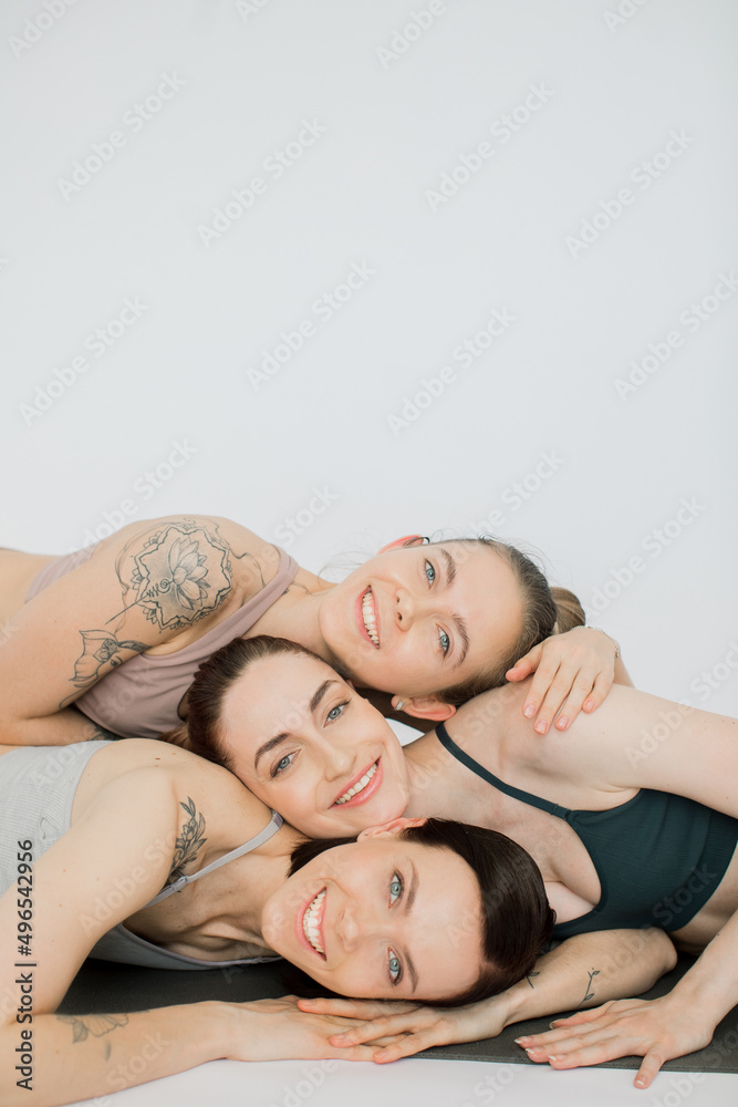 three beautiful women smiling bowed their heads over each other, hugging each other.
girls rest after yoga practice and meditate in a women's circle on a white background three beautiful women smiling bowed their heads over each other, hugging each other.
girls rest after yoga practice and meditate in a women's circle on a white background