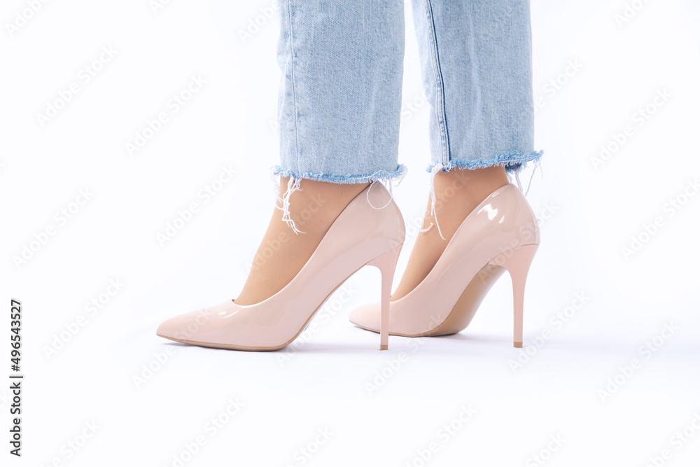 Slender female legs in patent leather shoes with high heels. Light blue ripped jeans. Fashion and Style. Side view