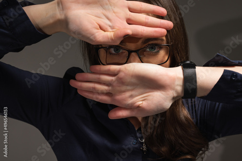 Close up portrait of cheerful girl in glasses showing happiness, smiling. She covers her face with her hand so that it pierces it, isolated on a white background, and there is room for a copy in