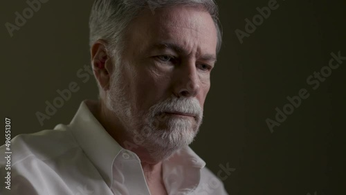 Portrait of a weary and fearful senior man in a dimly lit room. photo