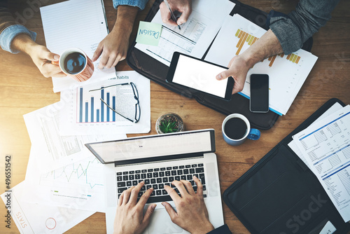 More gets done by working efficiently together. High angle shot of a group of unrecognisable businesspeople working together in an office.