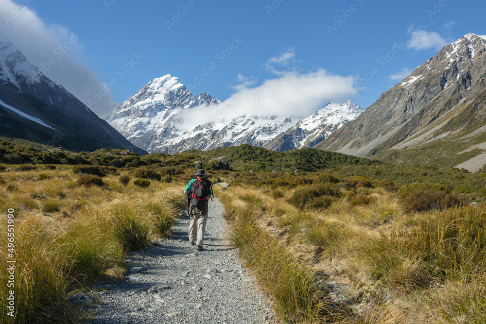 Man hiking Hooker Valley track, Mt Cook in the distance. South Island.