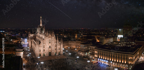 Aerial view of Piazza Duomo in front of the gothic cathedral in the center. Aerial view of the night Milan sky with stars and milky way galaxy in Italy.