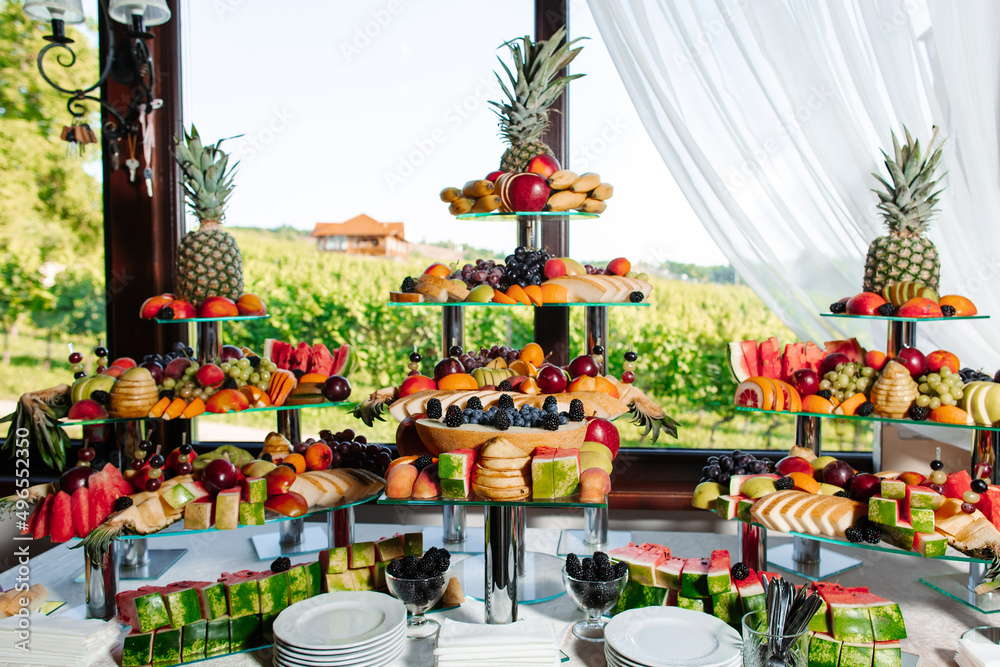 Fruit buffet for a wedding. Assortment of exotic fruits on the background of vineyards in the restaurant. Decoration of fresh fruit.