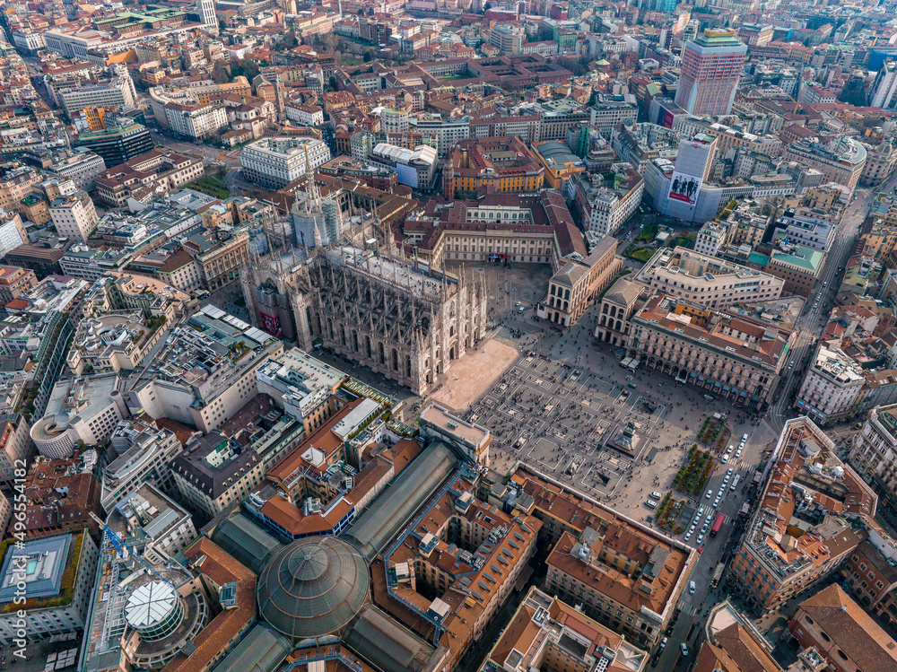 Obraz premium Aerial view of Piazza Duomo in front of the gothic cathedral in the center. Drone view of the gallery and rooftops during the day. Milan. Italy,