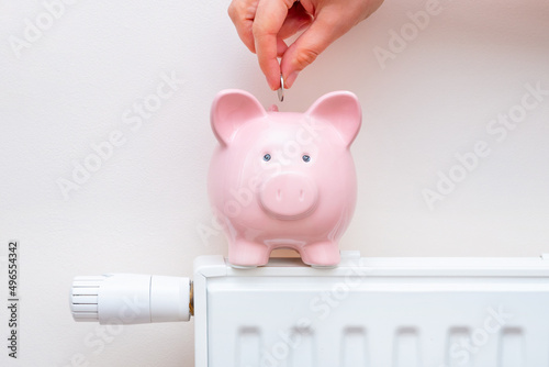 Piggy bank on radiator. Heating cost concept photo