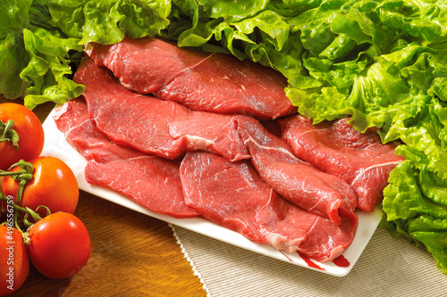 Raw rib eye beef steak with tomatoes and green salads