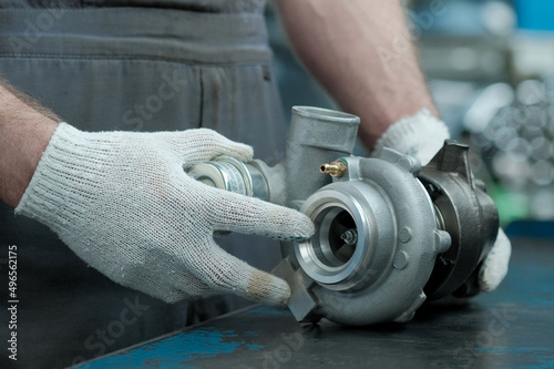 A turbine for an automobile engine on the desktop of an auto mechanic. Maintenance and repair of the car in the car service. Inspection of the spare part before replacement on the engine.