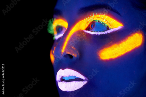 Neon celebration. A young woman with with neon paint on her face posing. photo