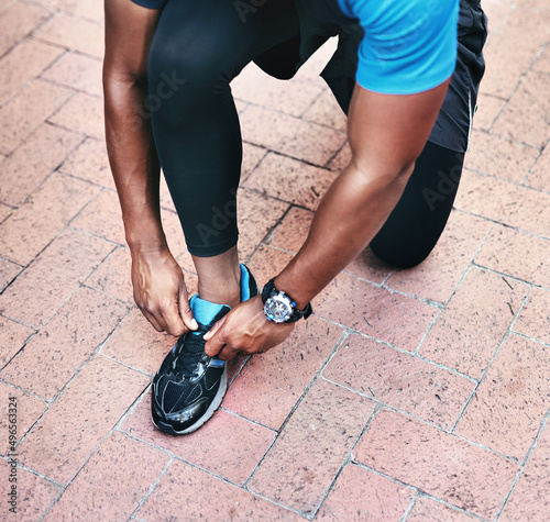 Life is a race you run at your own pace. Shot of an unrecognizable man tying his shoelaces while exercising outdoors in the city.