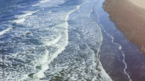 Aerial sun setting over sea ocean, tropical seascape coastline from above. On a summer evening on the seashore, a beautiful sea sunset, sea waves with white foam wash the sandy beach.