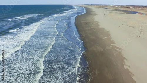 On a summer evening on the seashore, a beautiful sea sunset, sea waves with white foam wash the sandy beach. Aerial sun setting over sea ocean, tropical seascape coastline from above.