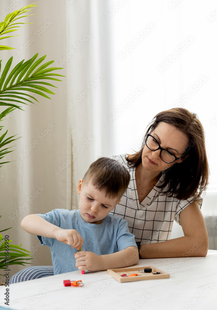 Montessori material. Woman and a boy are studying a puzzle with keys and locks. Montessori material. Woman and a boy are studying a puzzle with keys and locks.