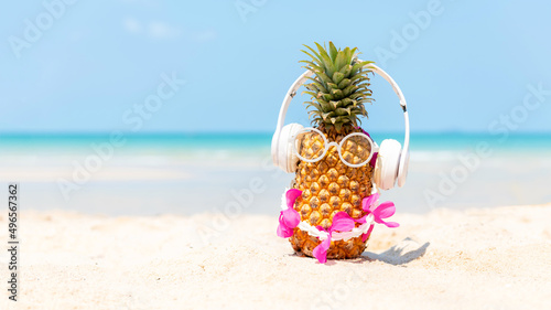 Fototapeta Naklejka Na Ścianę i Meble -  Summer in the party.  Hipster Pineapple Fashion in sunglass and listen music with sunblock and sandal on the sand beach beautiful blue sky background.  Creative art fruit for tropical style