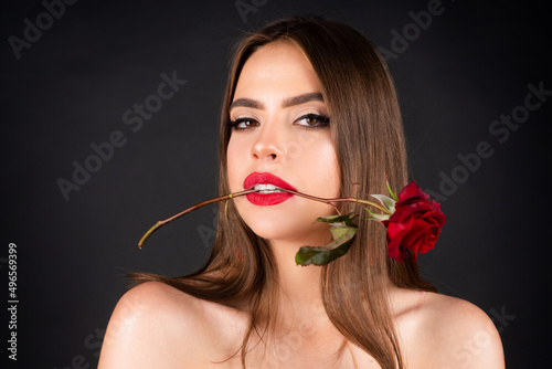 Seductive sensual woman holding red rose with teeth. Close-up portrait of young beautiful sexy woman with red rose. Birthday day.