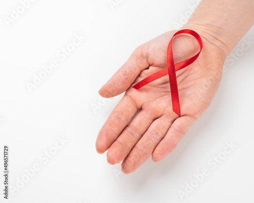 Female palm with a red ribbon on a white background. Symbol of the fight against AIDS.