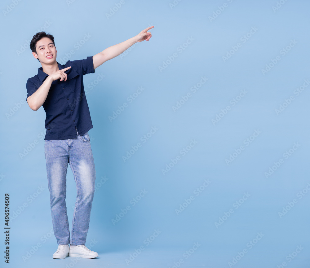 Full length image of young Asian man posing on blue background Full length image of young Asian man posing on blue background