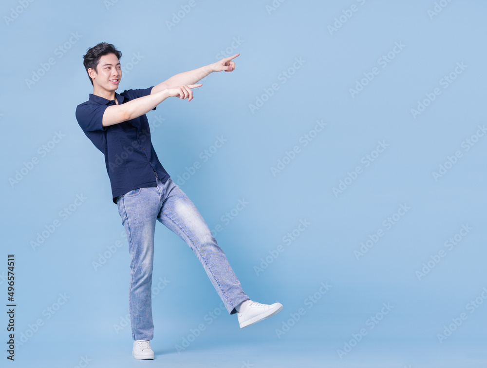 Full length image of young Asian man posing on blue background