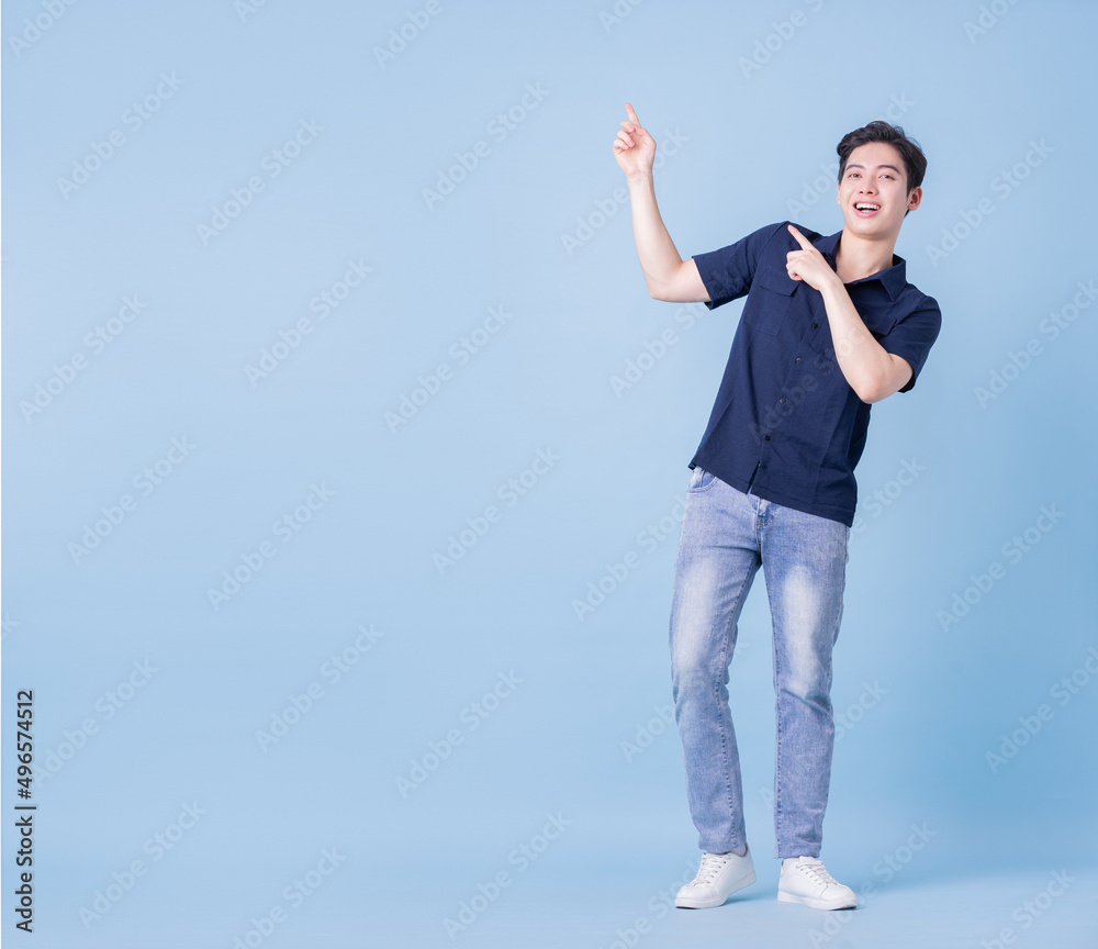 Full length image of young Asian man posing on blue background Full length image of young Asian man posing on blue background