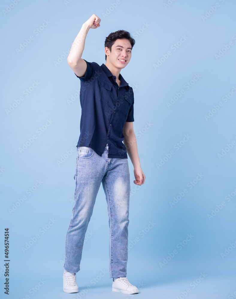 Full length image of young Asian man posing on blue background Full length image of young Asian man posing on blue background
