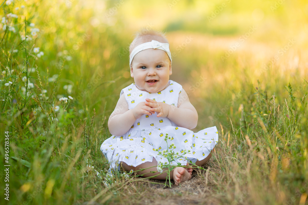 charming little girl in a white dress is sitting on a flower meadow. child playing outdoors charming little girl in a white dress is sitting on a flower meadow. child playing outdoors