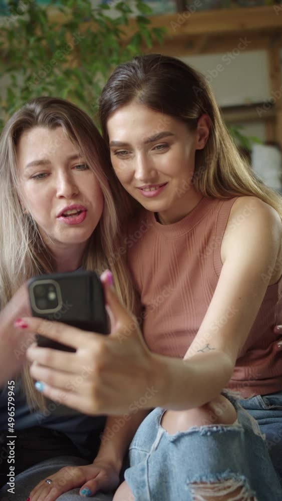 Two young lgbt ladies are talking with their friends on the video call, listening attentively and smiling, slow motion Two young lgbt ladies are talking with their friends on the video call, listening attentively and smiling, slow motion