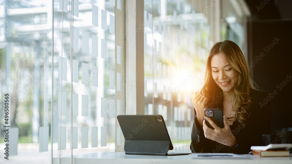 Woman gesturing and looking at a smartphone screen, businesswoman checking company monthly sales and pretending to be happy as sales meet planned targets according to policy. Sales management concept. Woman gesturing and looking at a smartphone screen, businesswoman checking company monthly sales and pretending to be happy as sales meet planned targets according to policy. Sales management concept.