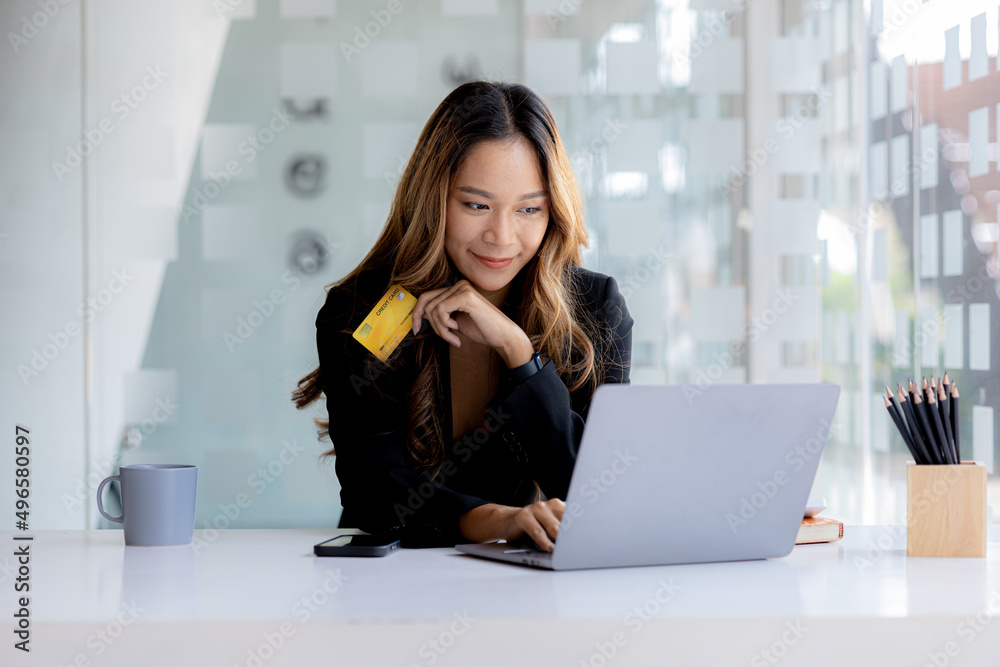 Beautiful woman holding a credit card, she uses a credit card to pay for goods and services online, the concept of using a credit card for online shopping, ordering goods and services on the website. Beautiful woman holding a credit card, she uses a credit card to pay for goods and services online, the concept of using a credit card for online shopping, ordering goods and services on the website.