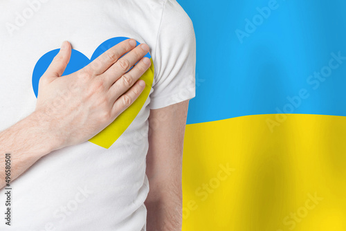 Man with heart made of flag of Ukraine on Ukrainian flag background. Help Ukraine concept
