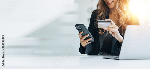 Beautiful woman holding a credit card, she uses a credit card to pay for goods and services online, the concept of using a credit card for online shopping, ordering goods and services on the website. photo