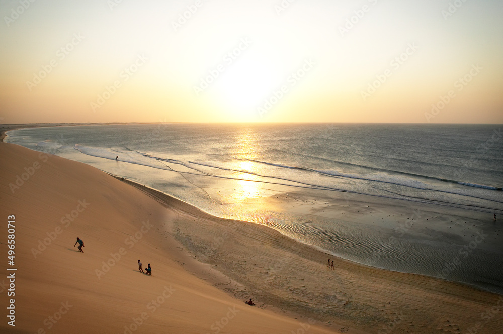 People step up sand dunes at sunset People step up sand dunes at sunset