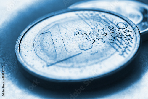 Euro coins. The focus is on the inscription with the name of the Eurozone currency on the 1 euro coin. Close-up. Blue tinted illustration about the economy news of the European Union. Macro photo