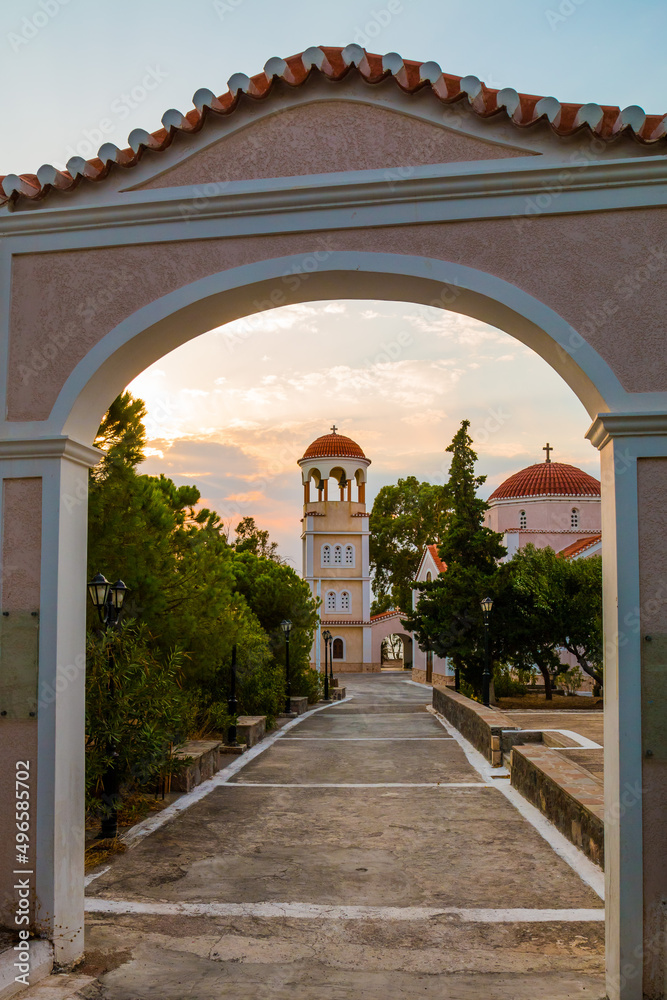 Entrance, Gate to the Ekklisia Agios Sozon Church in Perdika, Aegina, Greece with dramatic clouds in the background