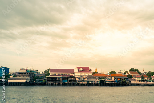 View from a passenger ship on a tropical landscape background of a community in Bangkok adjacent to Thailand's Chao Phraya River.