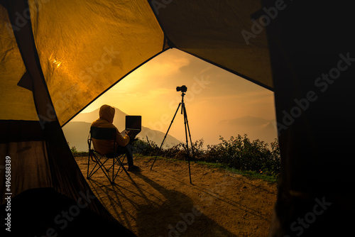 Travel Photographer with laptop sits on top view on the mountain, blogger taking photos and working on laptop, Traveling camping and freelancing concept 